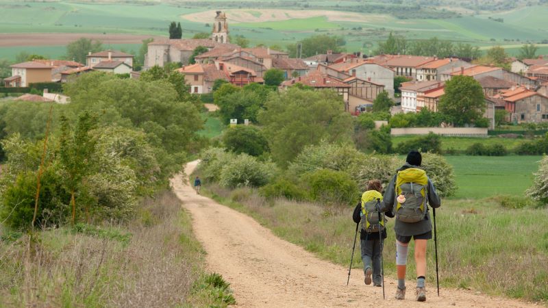 Tv� pilgrimsvandrare n�rmar sig en v�rgr�n by p� den spanska landsbygden.by 